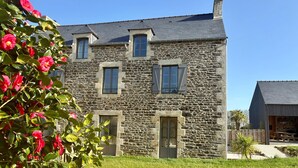 A stone house with a sloped roof, multiple windows, and a front door. - Lovely Holiday Cottage in Corseul (Corseul)