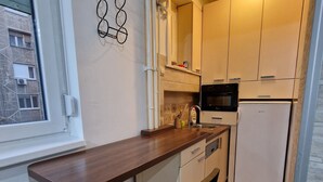 Eine kleine Küche mit Holztischplatte, einem schwarzen Stuhl und einer eingebauten Mikrowelle.