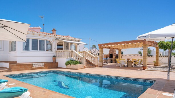 A swimming pool with lounge chairs, a covered patio area, and a house with a balcony. - Private villa with barbecue, ping pong, swimming pool and garden. 7 min from the beach! (Cala en Porter)