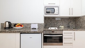 A compact kitchen with a microwave, toaster, kettle, and a small refrigerator. - Central Studio Apartment. Communal Heated Pool (CN)