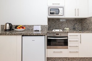 A compact kitchen with a microwave, toaster, kettle, and a small refrigerator. - Central Studio Apartment. Communal Heated Pool (CN)
