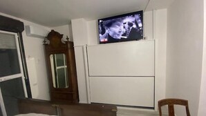 A bedroom with a bed, a wooden chair, a television mounted on the wall, and a wardrobe. - Appartamento Perugia 705/B (Perugia)