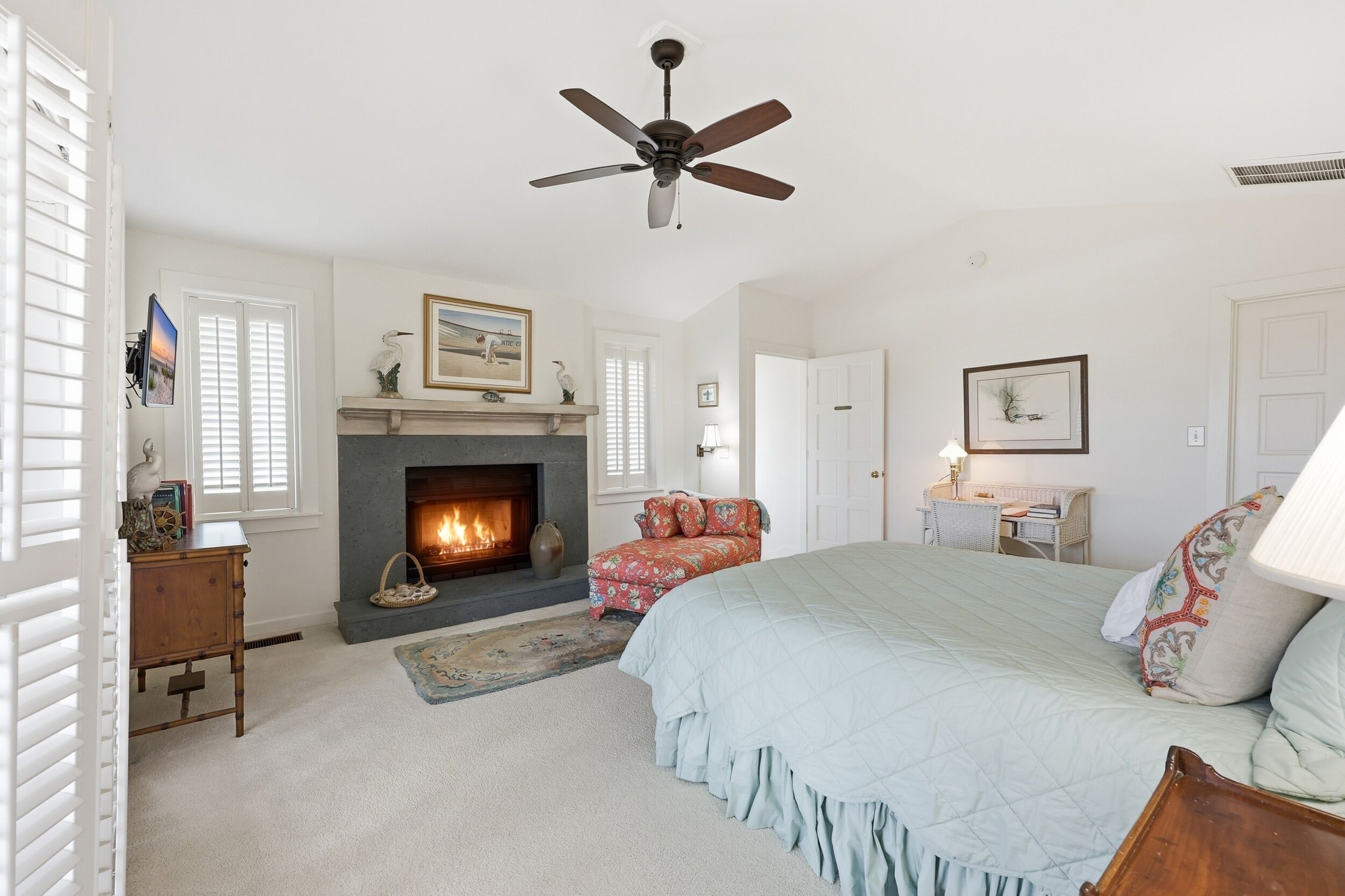 A bedroom with a fireplace, a bed, a desk, and a chair.