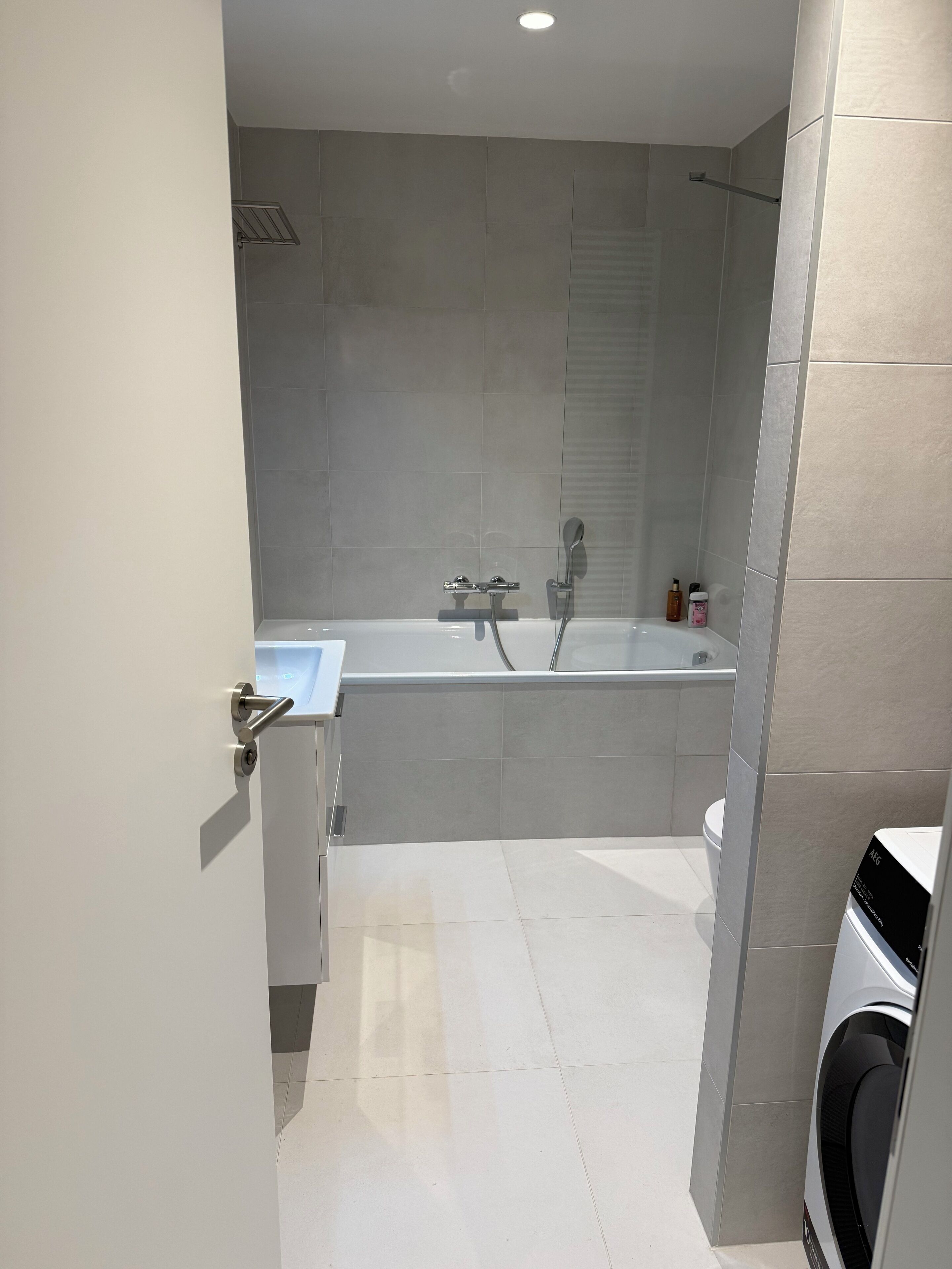 A modern bathroom with a bathtub, toilet, and a washing machine.