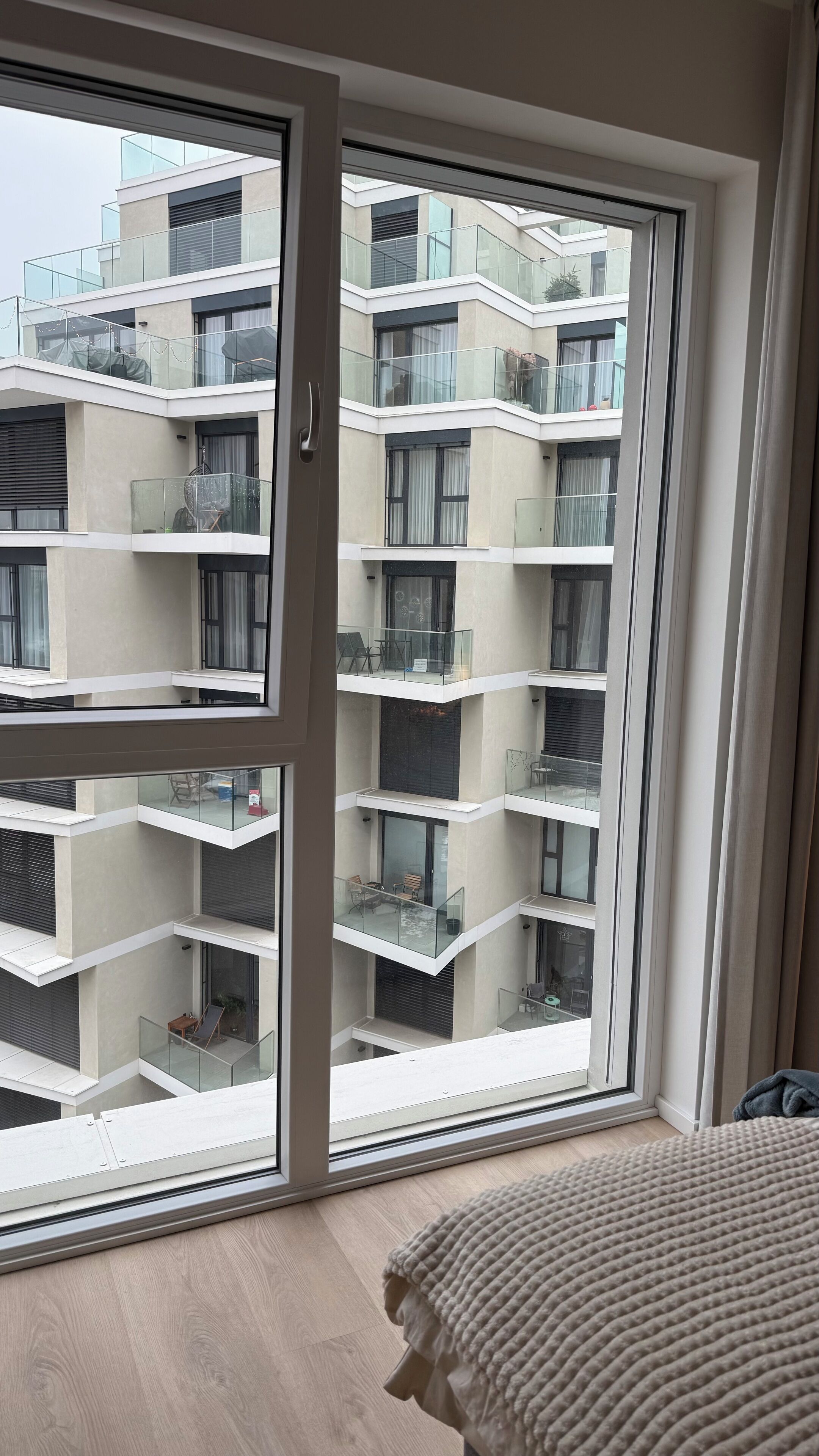 A modern apartment with a large sliding glass door leading to a balcony. The apartment features a multi-level design with balconies on each floor.