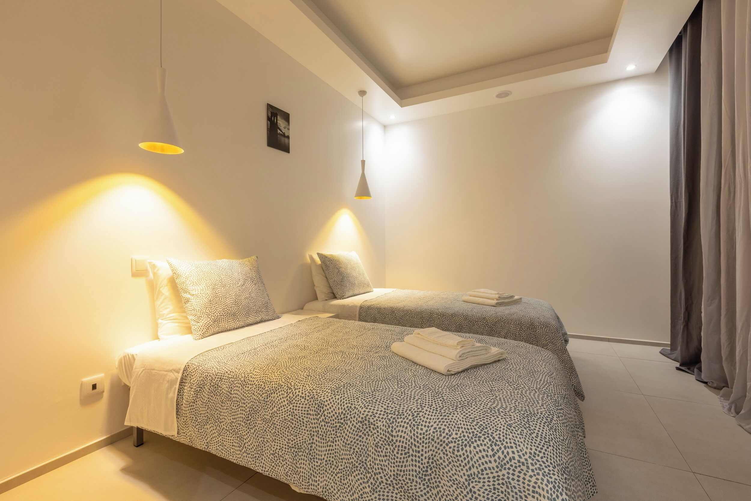 Una camera da letto con due letti, ognuno con biancheria a motivi e un asciugamano piegato sul comodino.