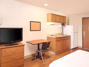 Une chambre d’hôtel compacte équipée d’une kitchenette, d’une télévision, d’un bureau et d’une chaise.
