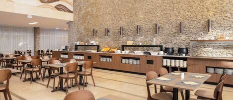 A restaurant with a stone wall, wooden tables, and chairs.