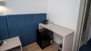 A compact room with a blue sofa, a small desk with a phone and cups, and a compact refrigerator. - Alemaris Resort (Baška Voda)