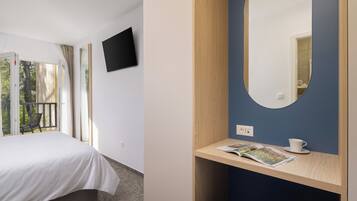 A bedroom with a bed, a TV mounted on the wall, and a window with curtains.