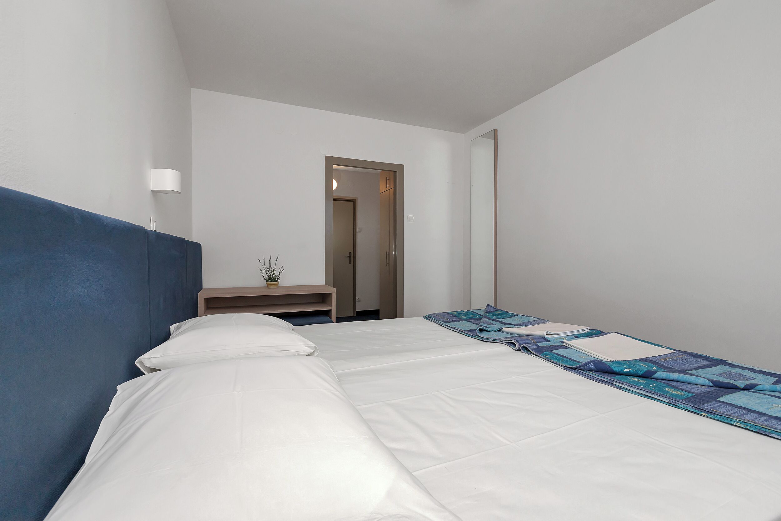 Ein Hotelzimmer mit einem großen Bett, einem Nachttisch und einer Tür zu einem weiteren Raum.