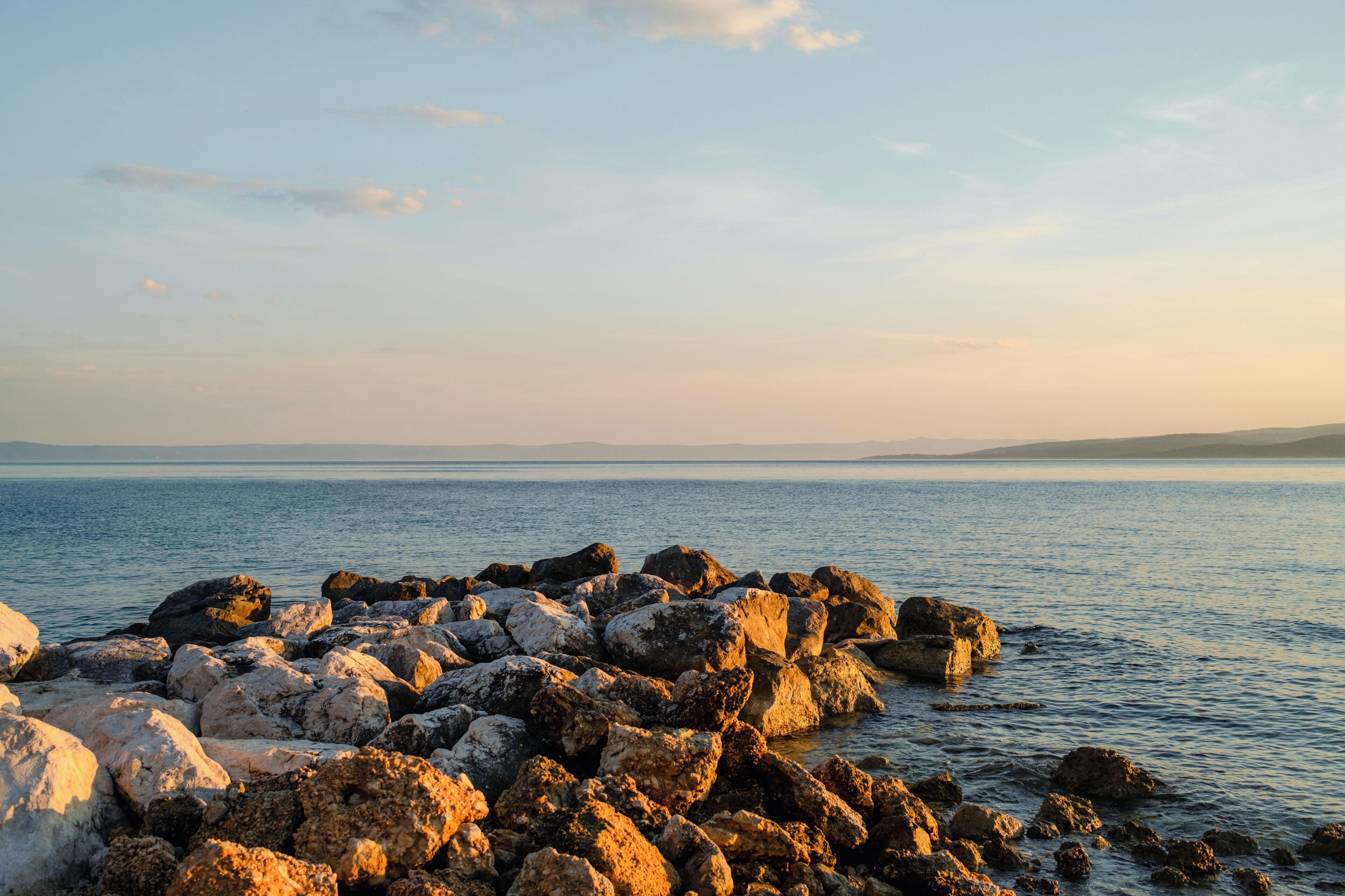 A rocky shoreline with calm water and distant land.