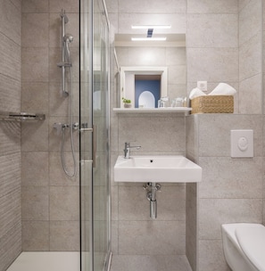 A modern bathroom with a glass-enclosed shower, a white sink, and a toilet. - Alemaris Resort (Baška Voda)