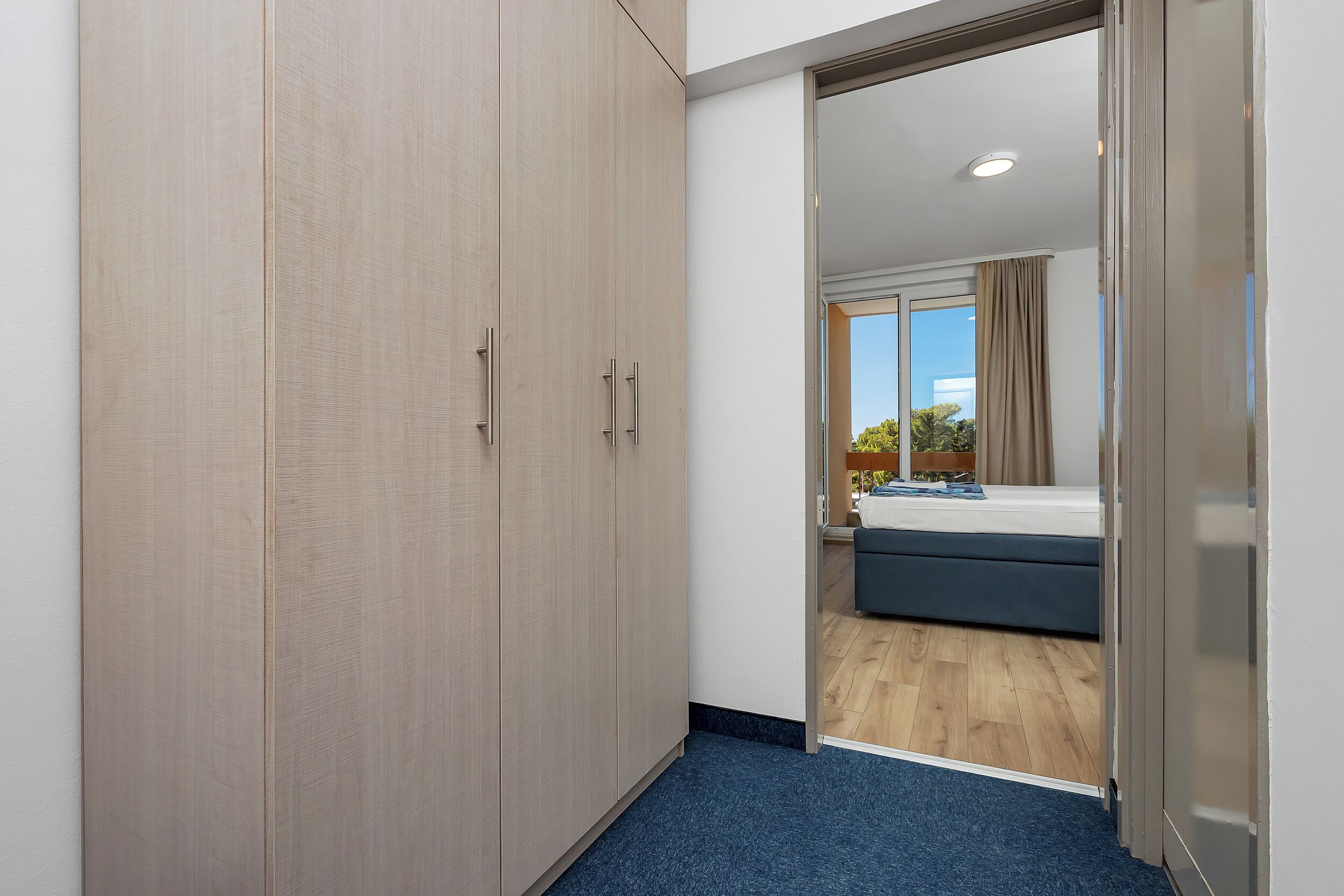 Een slaapkamer met een bed, een kledingkast en uitzicht.