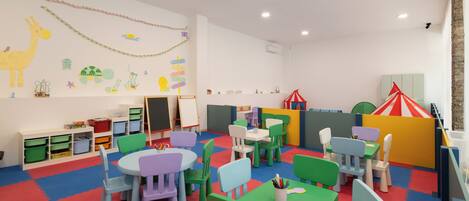 A children's playroom with colorful furniture, educational wall decorations, and a play area.