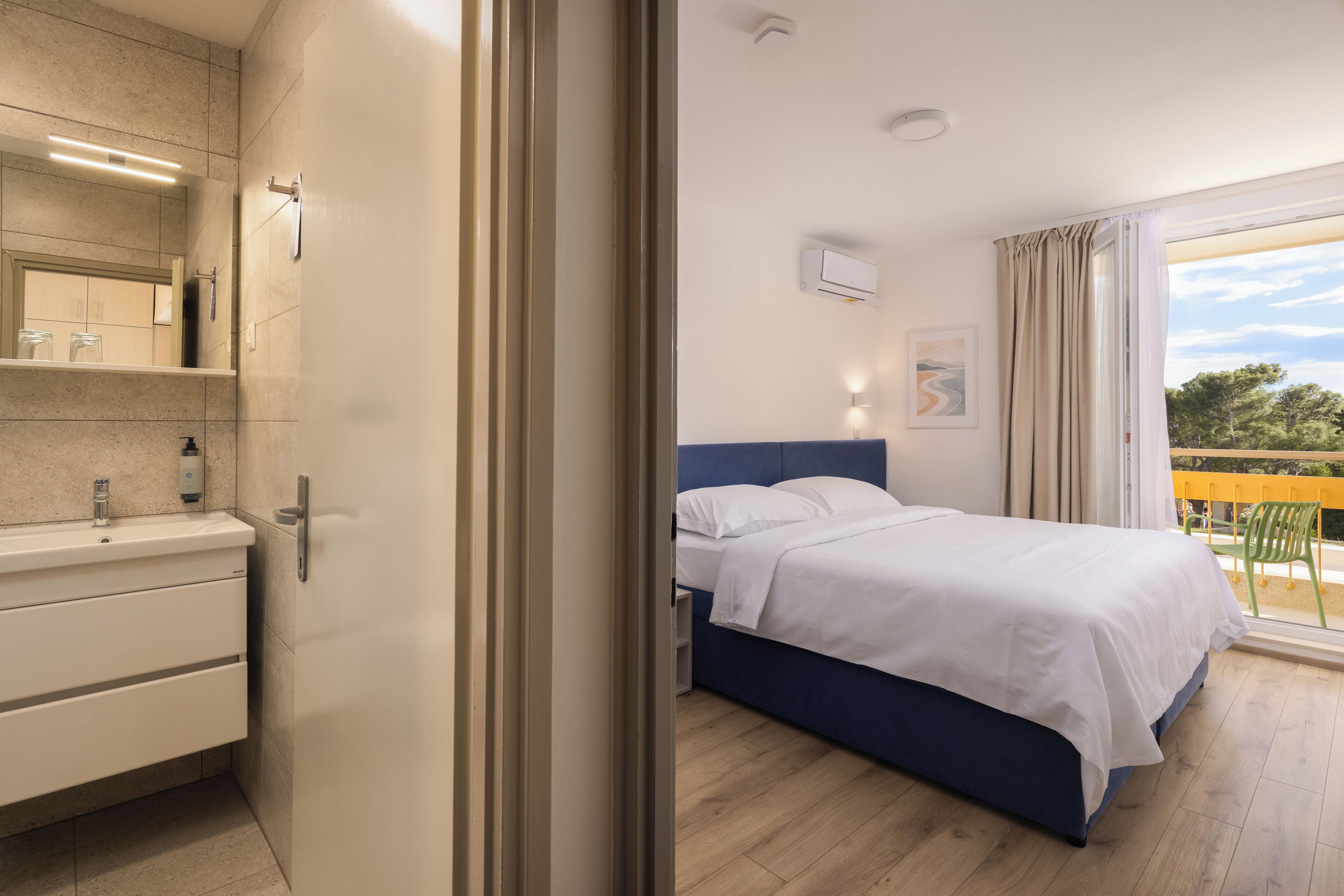 A modern bedroom with a bed, bedside table, and a window with a view.