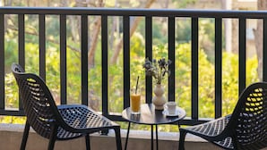 A balcony with two chairs, a small table, a glass of juice, a cup, and a vase with flowers. - Alemaris Resort (Baška Voda)