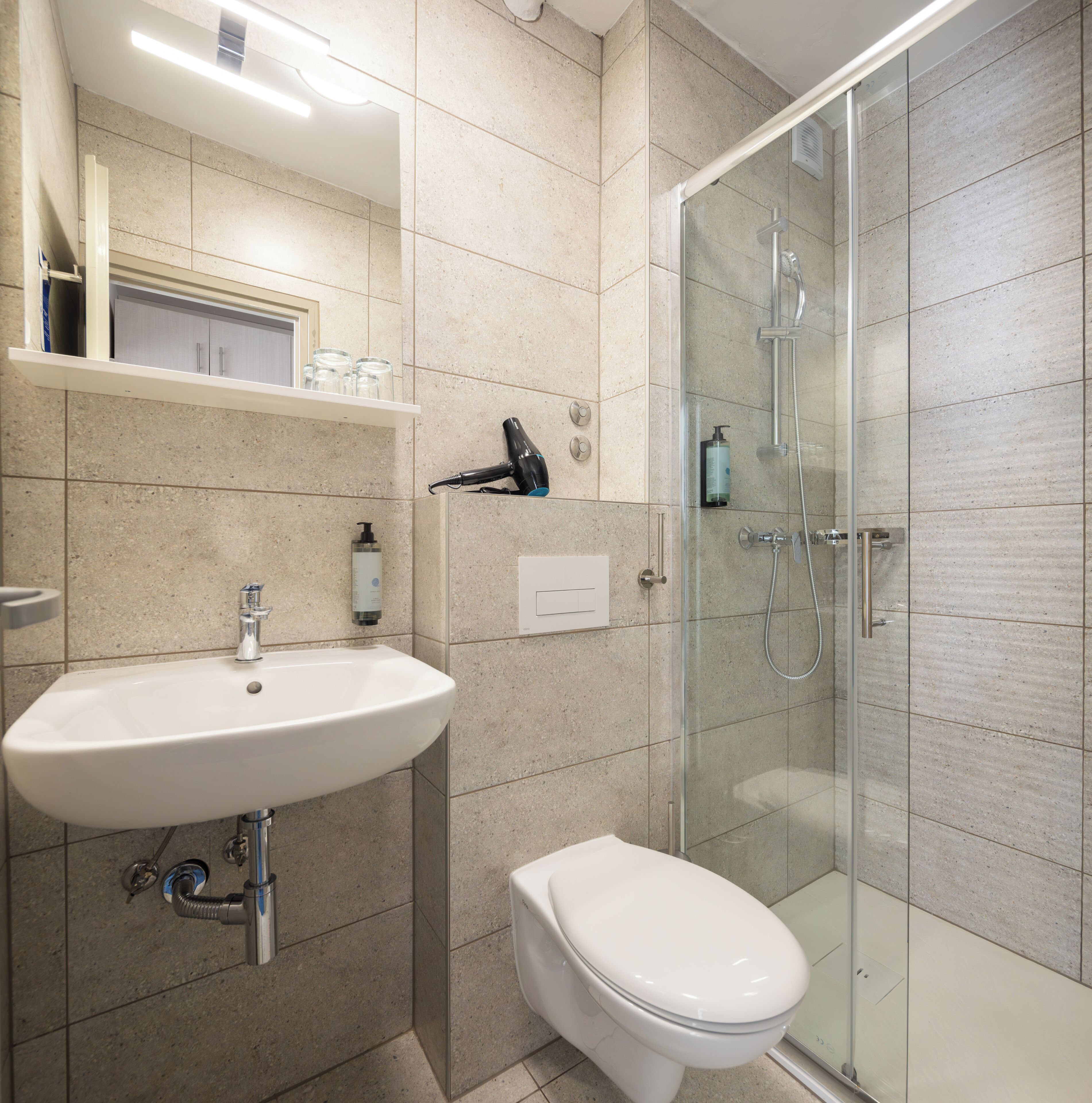 A modern bathroom with a sink, toilet, and glass shower enclosure.