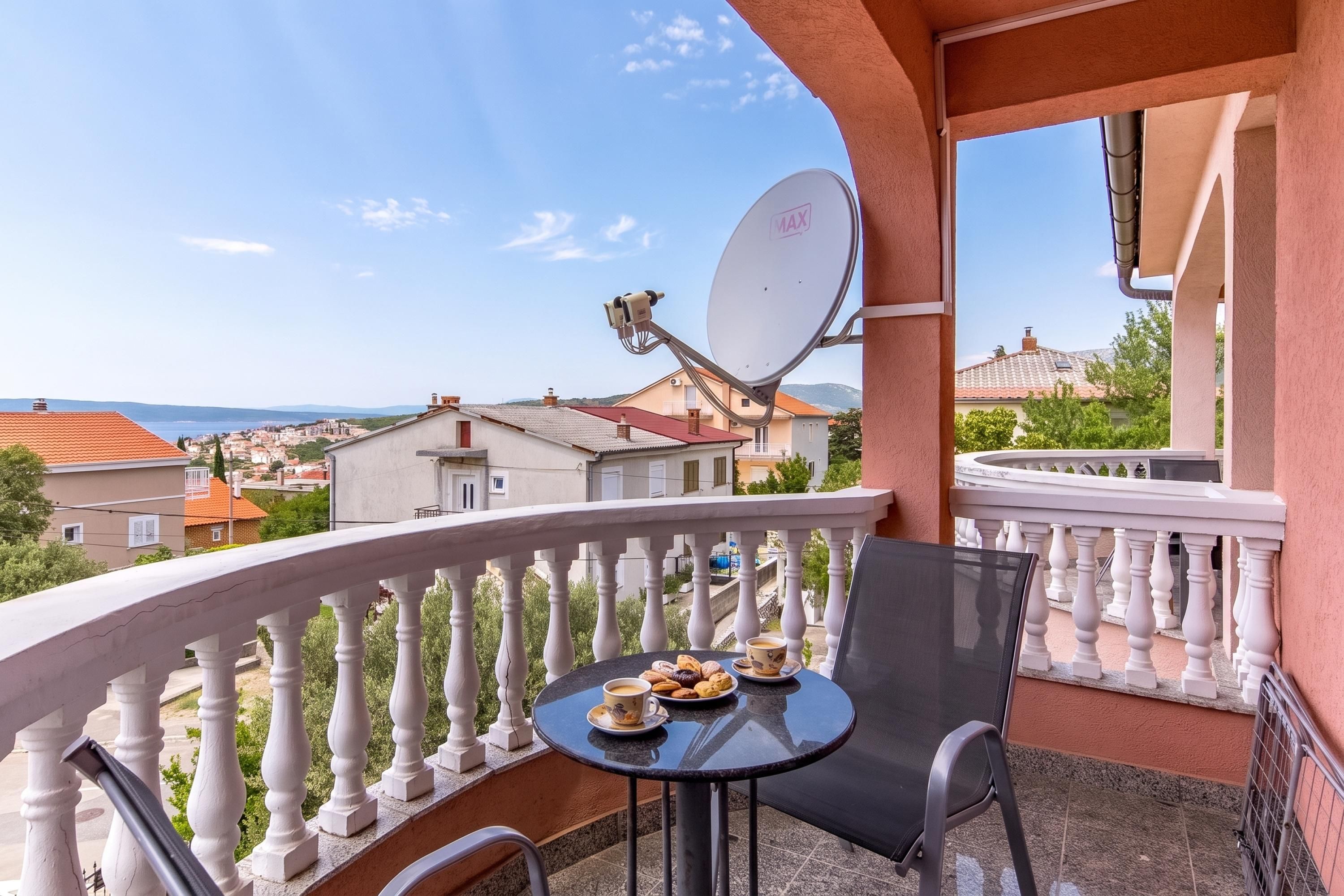 A balcony with a table, chair, and satellite dish.