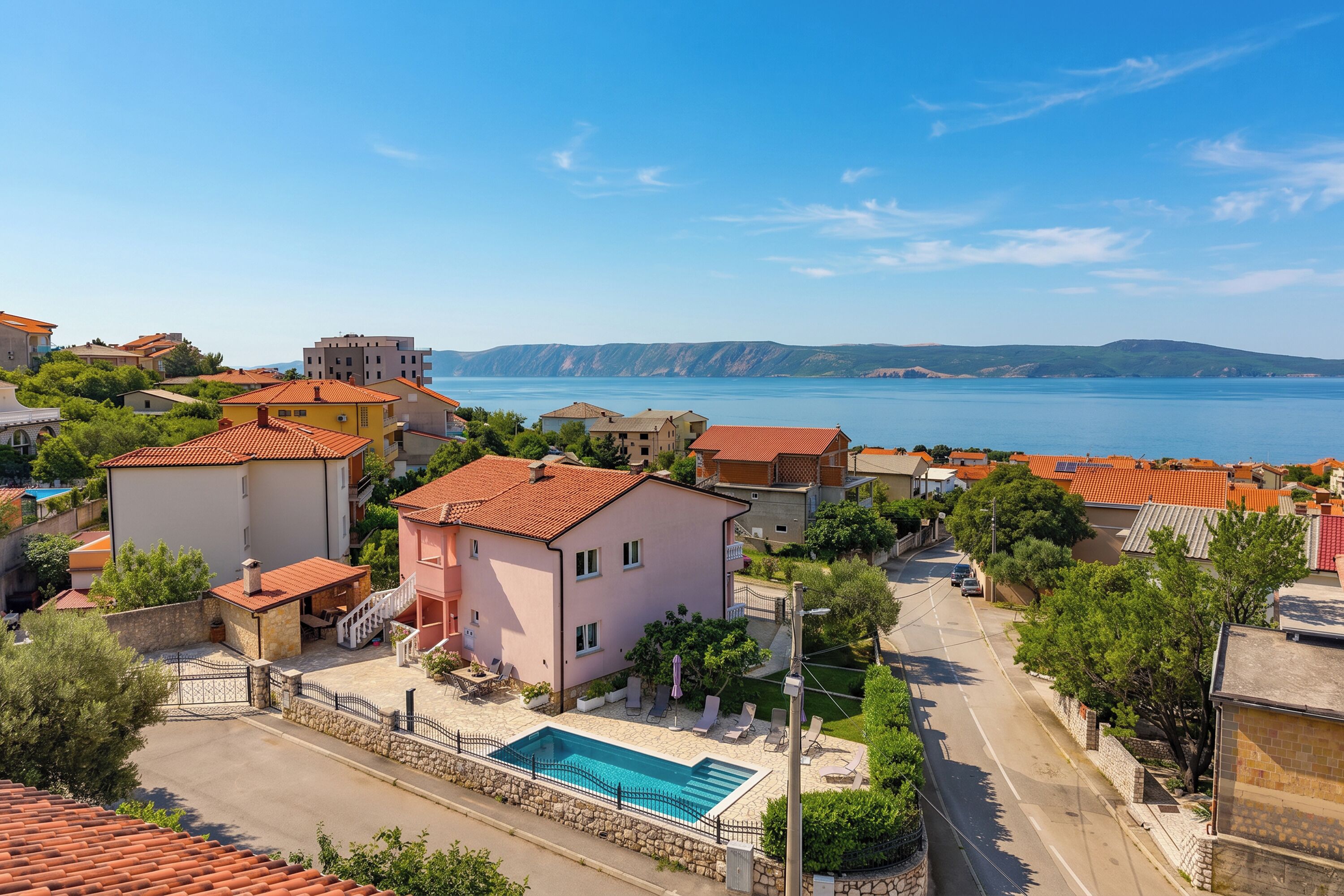 A residential area with houses, a swimming pool, and a view of the sea.