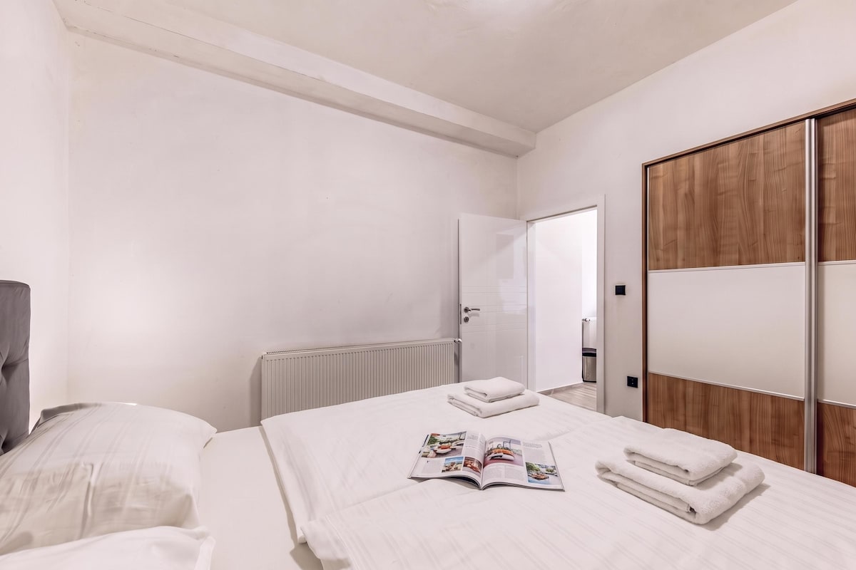 A hotel room with a bed, a bedside table with a book, and a wardrobe.