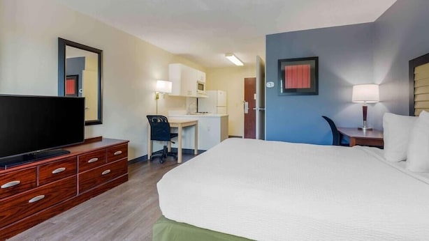 Une chambre d’hôtel comprenant un lit, un bureau avec une chaise, une télévision et un miroir.