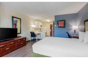 Ein Hotelzimmer mit Bett, Schreibtisch, Stuhl, Fernseher und Kleiderschrank.