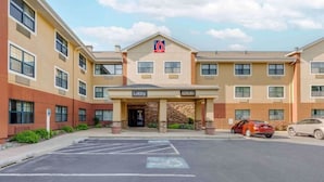 Un hôtel à plusieurs étages, doté d’un hall d’entrée, d’un parking et d’un panneau indiquant le numéro « 6 » au-dessus de l’entrée.