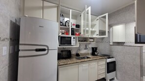 Une cuisine moderne avec des meubles blancs, un four à micro-ondes encastré, une machine à café et une cuisinière.