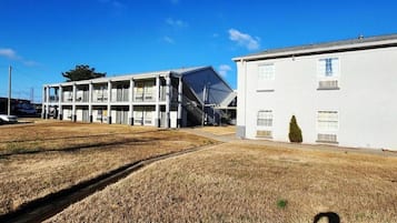 A motel with a two-story structure, a parking lot, and a grassy area.