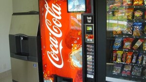 A vending machine with a Coca-Cola logo and a snack vending machine next to it. - Jacksonville Inn (Jacksonville)