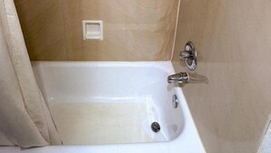 A bathroom with a white bathtub, a showerhead, and a wall-mounted faucet. - Jacksonville Inn (Jacksonville)