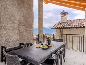 A terrace with a table set for dining, a potted plant, and a bottle of wine. - Riflessi by Interhome (Colico)