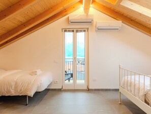 A bedroom with a bed, a window, an air conditioning unit, and a balcony. - Riflessi by Interhome (Colico)