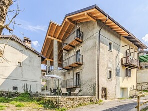 A multi-story building with balconies, a covered outdoor seating area, and a stone wall. - Riflessi by Interhome (Colico)