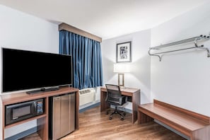 Ein Hotelzimmer mit Flachbildfernseher, Schreibtisch mit Stuhl, Lampe, Heizung und Kleiderhaken.
