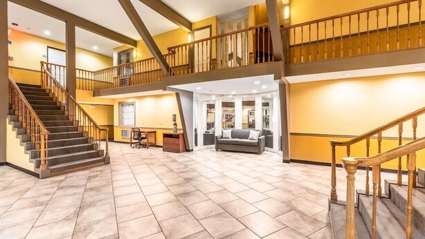 A spacious lobby with a staircase, a sofa, and a desk. - Americas Best Value Inn Searcy (Searcy)