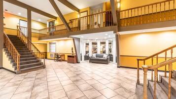 A spacious interior with a staircase, a seating area, and a reception desk.
