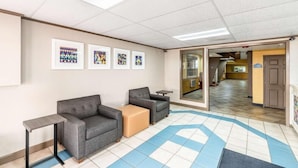 A waiting area with a sofa, chairs, a small table, and artwork on the wall. - Americas Best Value Inn Searcy (Searcy)