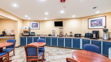 A hotel breakfast area with a counter, seating, and a mounted television.