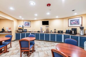 A hotel breakfast area with a counter, seating, and a mounted television. - Americas Best Value Inn Searcy (Searcy)