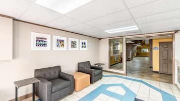 A reception area with a sofa, chairs, a small table, and framed artwork on the wall.
