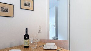 Una mesa de comedor con una botella de vino, copas y vajilla blanca.