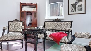 Una habitación con sofá, dos sillones, una mesita, un espejo y ventana con vistas.