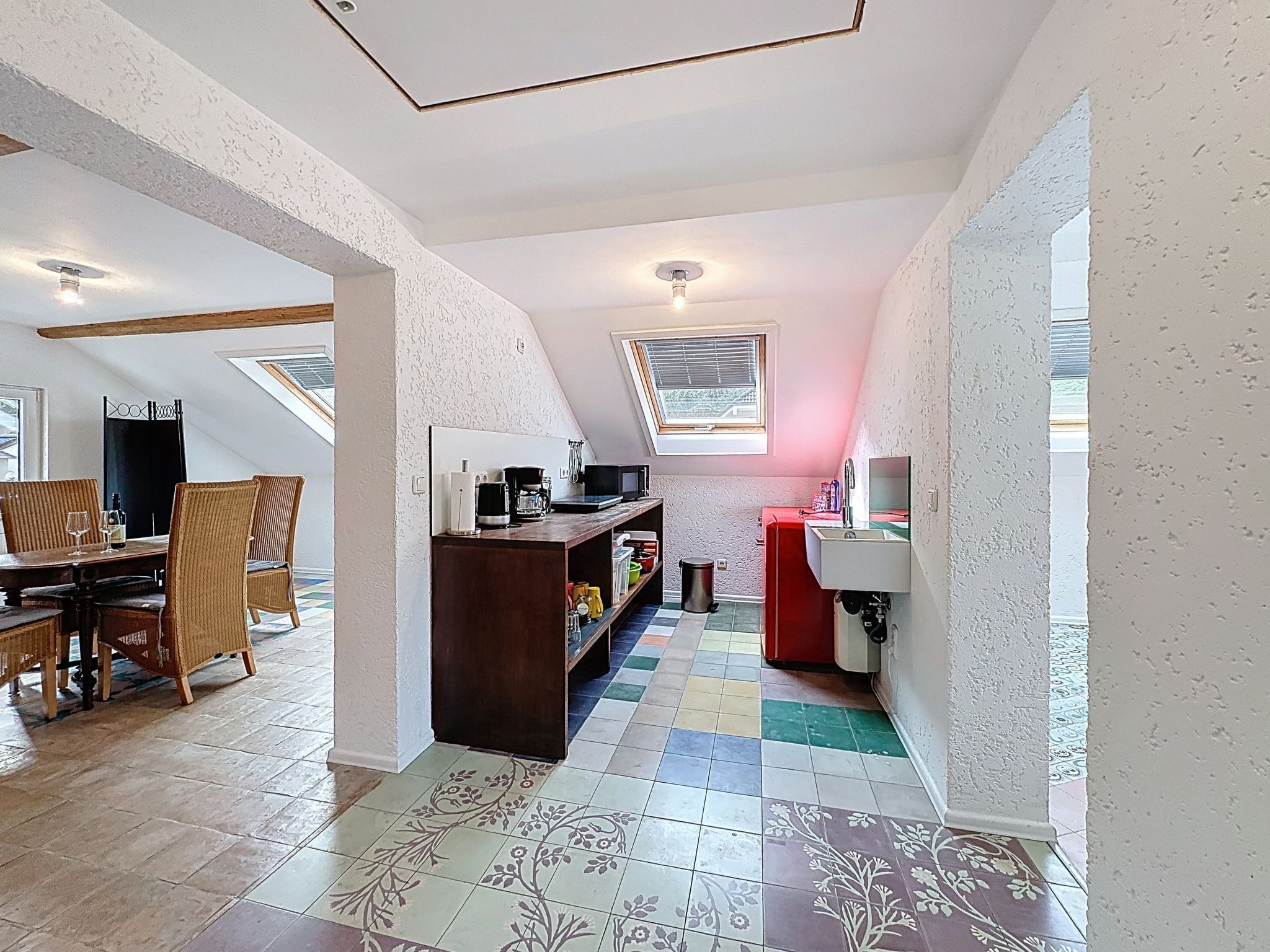 A compact kitchen with a dining area, a small window, and a red sink.