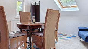 A dining area with wicker chairs, a round table, and a bottle of wine. - Wohnung 5 by Interhome (Sankt Goar)