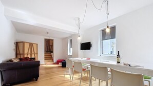 A modern living room with a sofa, dining area, and a TV mounted on the wall. - Apartmenthaus 110 by Interhome (Sankt Goar)