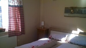 A bedroom with a bed, a nightstand, a lamp, and a window with curtains.