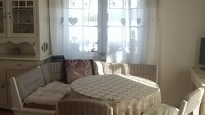 A cozy room with a round table, cushioned seating, and a cabinet with glass doors.