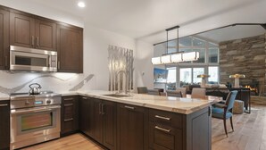 A modern kitchen with dark wood cabinets, stainless steel appliances, and a large island. - Ski Retreat Hot Tub 2br + Loft 2 Bedroom Condo (Park City)